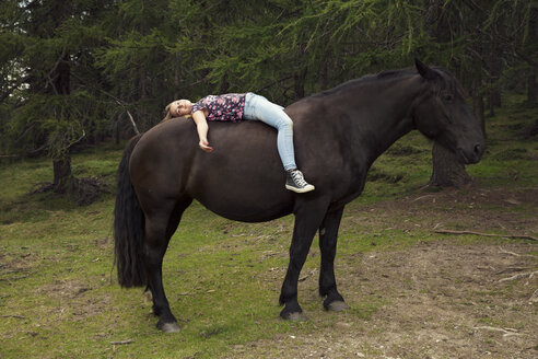 Mädchen auf dem Rücken eines Pferdes auf einer Waldlichtung, Sattelbergalm, Tirol, Österreich - CUF23463