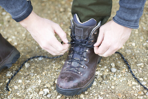 Beschnittene Ansicht eines Mannes, der einen Wanderschuh schnürt - CUF23477