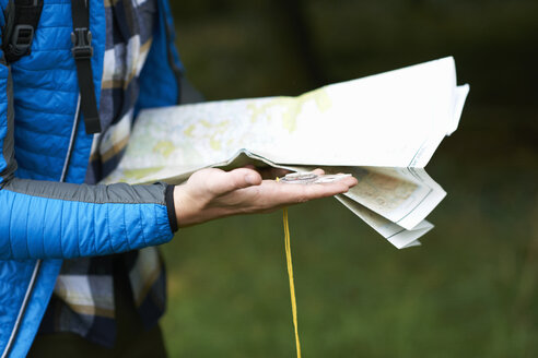 Ausschnitt eines Wanderers mit Blick auf eine Papierkarte und einen Kompass - CUF23478