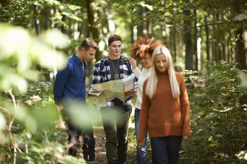 Mann wandert mit Freunden im Wald und hält eine Karte - CUF23483