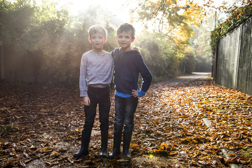 Porträt von Zwillingsjungen, im Freien, umgeben von Herbstblättern - CUF23510