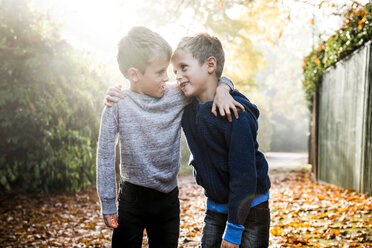 Portrait of twin boys, outdoors, face to face, surrounded by autumn leaves - CUF23511