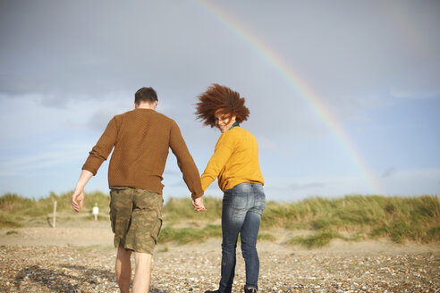 Paar geht am Strand in Richtung Regenbogen - CUF23540