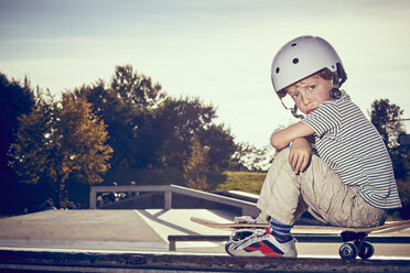 Junge sitzt auf Skateboard im Park - CUF23550