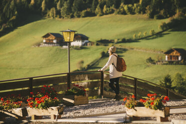 Frau genießt die Aussicht am Holzzaun, Santa Maddalena, Dolomiten, Val di Funes (Fünser Tal), Südtirol, Italien - CUF23559