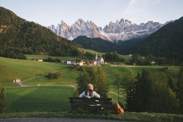 Woman relaxing on park bench, Santa Maddalena, Dolomite Alps, Val di Funes (Funes Valley), South Tyrol, Italy - CUF23561