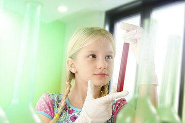 Girl pretending to be scientist examining test tube - CUF23571