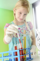 Girl pretending to be scientist removing test tube from rack - CUF23573