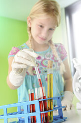 Mädchen, das vorgibt, Wissenschaftlerin zu sein, nimmt Reagenzglas aus dem Regal - CUF23573