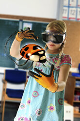 Girl pretending to be teacher wearing virtual reality headset and gloves to show ladybird - CUF23575