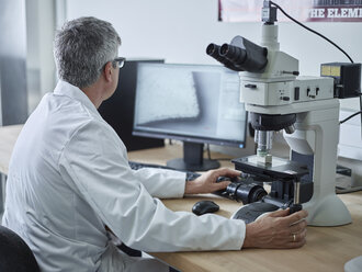 Physician working with microscope, looking on screen - CVF00720