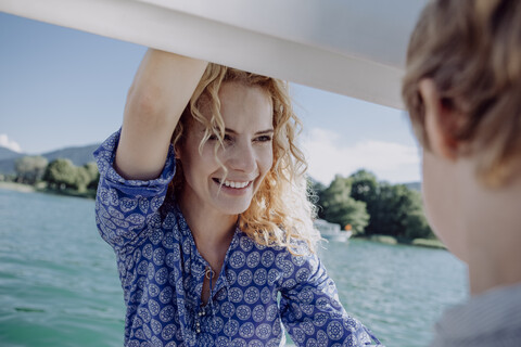 Lächelnde Mutter sieht ihren Sohn auf einem Segelboot an, lizenzfreies Stockfoto