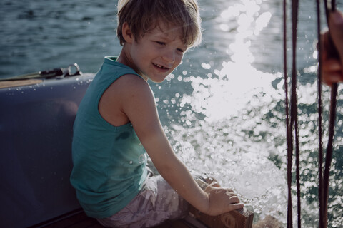 Lächelnder Junge auf einem Segelboot sitzend, lizenzfreies Stockfoto