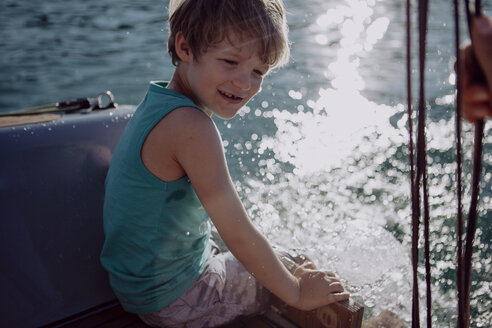 Smiling boy sitting on a sailing boat - JLOF00023