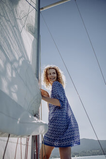 Smiling woman standing on a sailing boat - JLOF00052