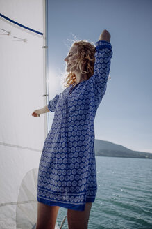 Smiling woman standing on a sailing boat - JLOF00054