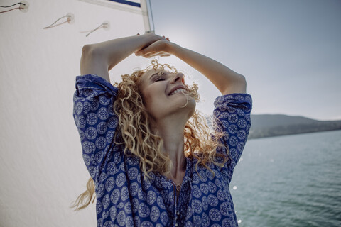 Unbekümmerte Frau auf einem Segelboot im Gegenlicht, lizenzfreies Stockfoto