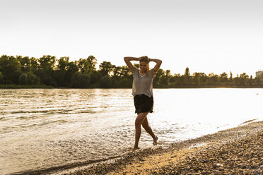 Junge Frau läuft barfuß am Flussufer - UUF14031