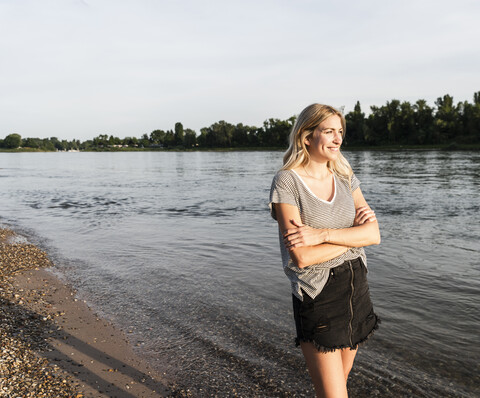 Blonde Frau am Flussufer am Abend, lizenzfreies Stockfoto