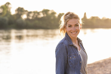 Portrait of blond woman at riverside in the evening - UUF14053