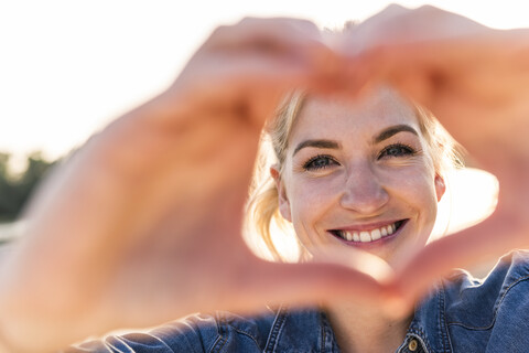 Woman making heart shape with hands and fingers stock photo