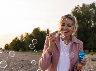 Laughing blond woman and soap bubbles - UUF14063