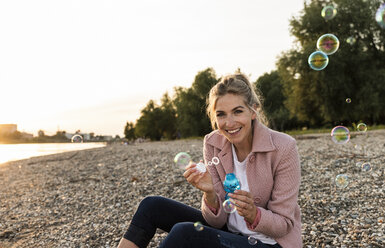 Laughing blond woman and soap bubbles - UUF14064