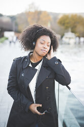 Young woman listening to headphones with eyes closed at Lake Como, Italy - CUF23606