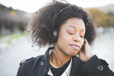 Close up of young woman listening to headphones with eyes closed at Lake Como, Italy - CUF23607