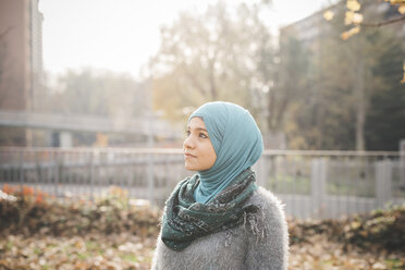 Porträt einer jungen Frau mit Hidschab, die in einen Park blickt - CUF23614