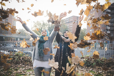 Zwei junge Frauen im Park, die Herbstblätter werfen - CUF23623