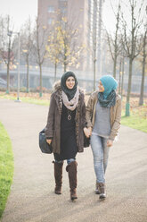 Zwei junge Frauen unterhalten sich bei einem Spaziergang im Park - CUF23624