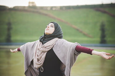 Junge Frau im Park mit geöffneten Armen und Hidschab - CUF23626