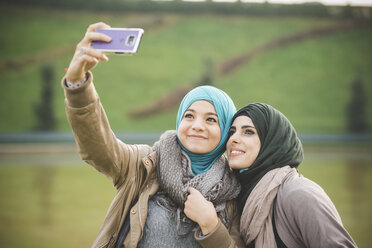 Zwei Freundinnen am Seeufer posieren für ein Smartphone-Selfie - CUF23666