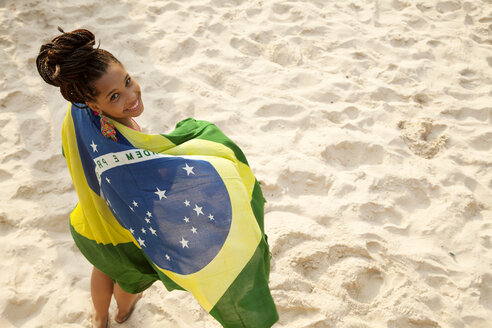 Porträt einer jungen Frau, die in die brasilianische Flagge eingewickelt ist, Strand von Ipanema, Rio De Janeiro, Brasilien - CUF23692