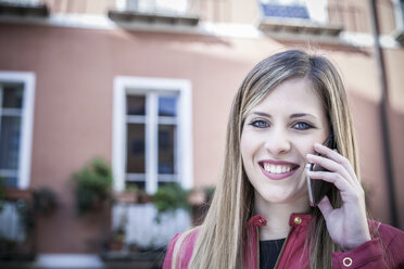 Portrait of young woman on street talking on smartphone, Cagliari, Sardinia, Italy - CUF23699