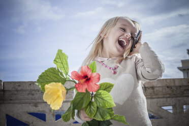 Junges Mädchen mit Blumen, lachend und auf dem Smartphone plaudernd, Cagliari, Sardinien, Italien - CUF23712