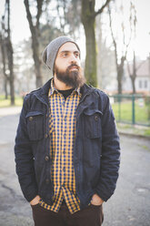 Portrait of mid adult man, standing in park, hands in pockets - CUF23728