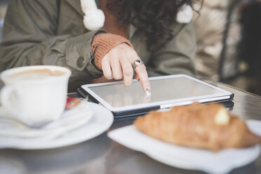 Ausgeschnittene Aufnahme einer jungen Frau, die in einem Straßencafé den Touchscreen eines digitalen Tablets benutzt - CUF23751