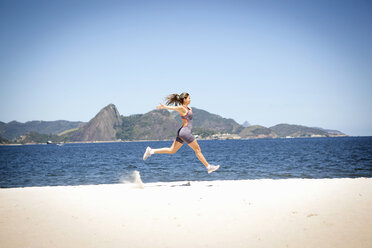 Junge Frau springt am Strand, Rio de Janeiro, Brasilien - CUF23789