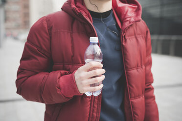 Ausgeschnittene Aufnahme eines jungen Mannes, der vor einem städtischen Büro Wasser trinkt - CUF23798