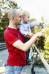 Father and son standing on bridge, looking at view, rural setting - CUF23817