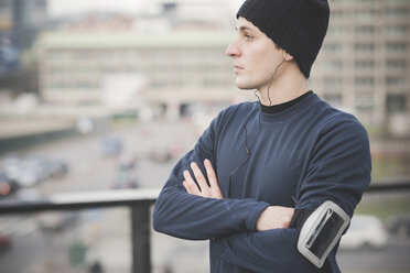 Portrait of young male runner looking out from footbridge - CUF23820