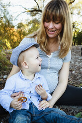 Mother and son sitting together, outdoors, in rural setting - CUF23831