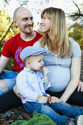 Porträt einer Mutter, eines Vaters und eines Sohnes, die zusammensitzen, im Freien, in ländlicher Umgebung, lizenzfreies Stockfoto