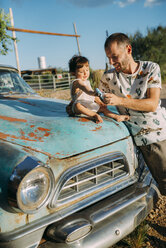 USA, Arizona, Vater und Baby spielen mit einer Nachbildung eines alten Oldtimers an der Route 66 - GEMF02060