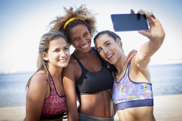 Three young women photographing themselves with phone - CUF23836