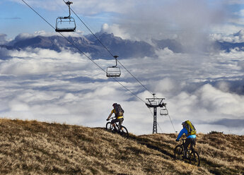 Zwei Mountainbiker unter Seilbahnen, Wallis, Schweiz - CUF23888