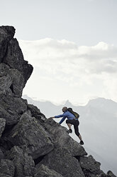 Mature man climbing up rocks, Valais, Switzerland - CUF23890