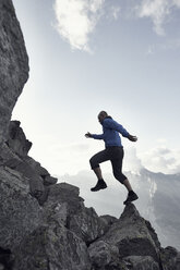 Mature man jumping on rocks, Valais, Switzerland - CUF23893